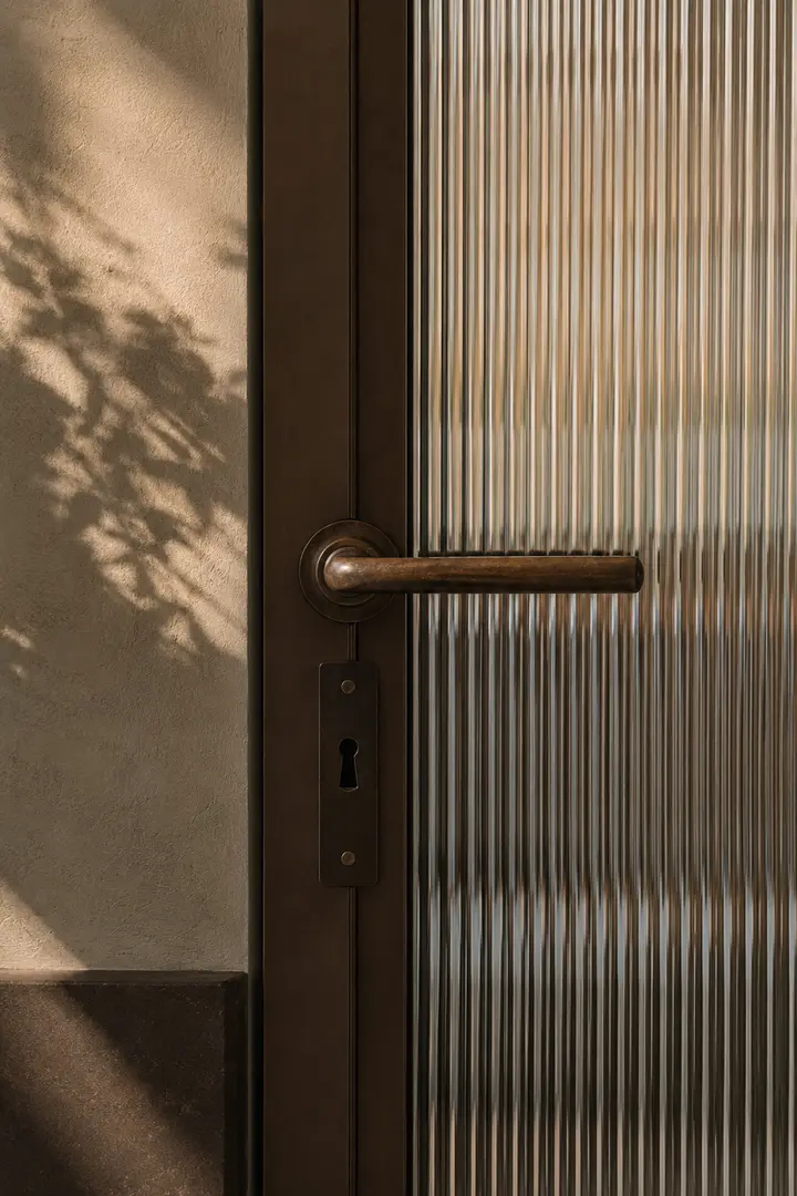 Dettaglio di una porta in vetro scanalato con maniglia in bronzo